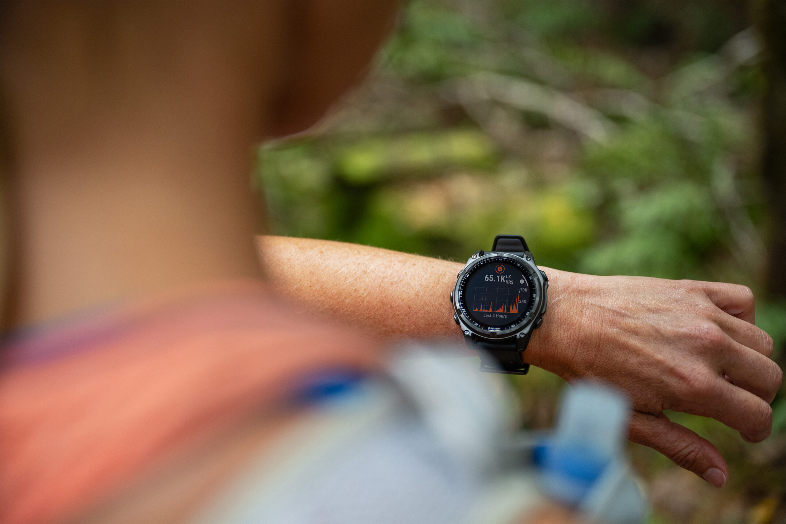 A person wearing a Garmin fenix 8 smartwatch looks at the solar charging feature.