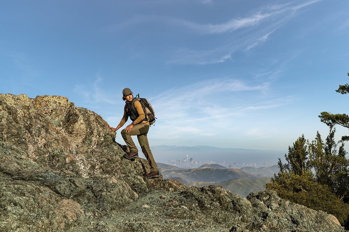 A man wearing a Garmin Instinct Crossover AMOLED smartwatch goes hiking.