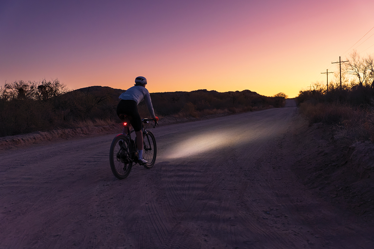 A cyclist using the Varia Vue smart headlight camera rides into a pink and yellow sunset.