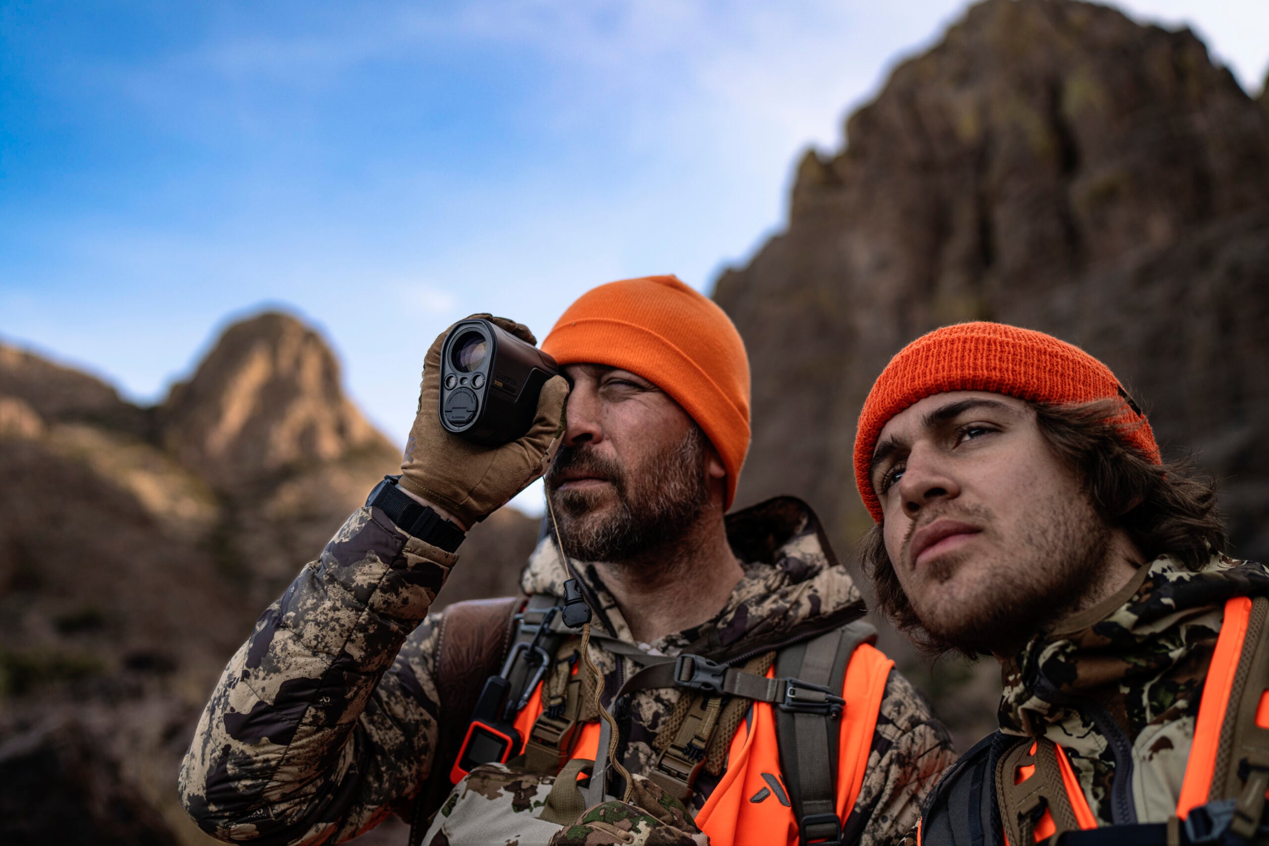 One man looking into the distance while the other looks into the L60i rangefinder. Both are in hunting gear.